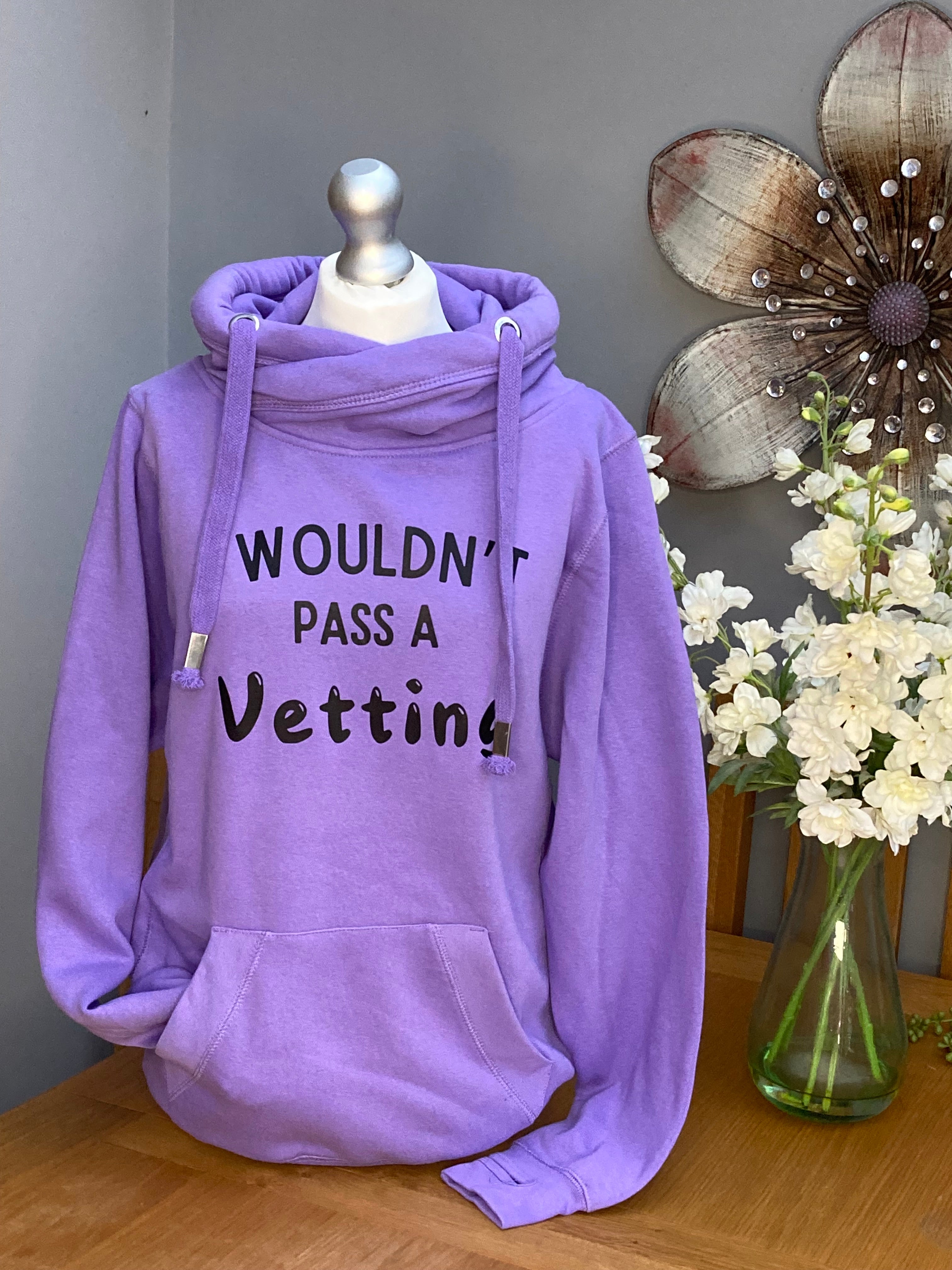 A lavender purple colour cross neck hood with hood and front pocket and slogan printed on the front saying I wouldn't pass a vetting 