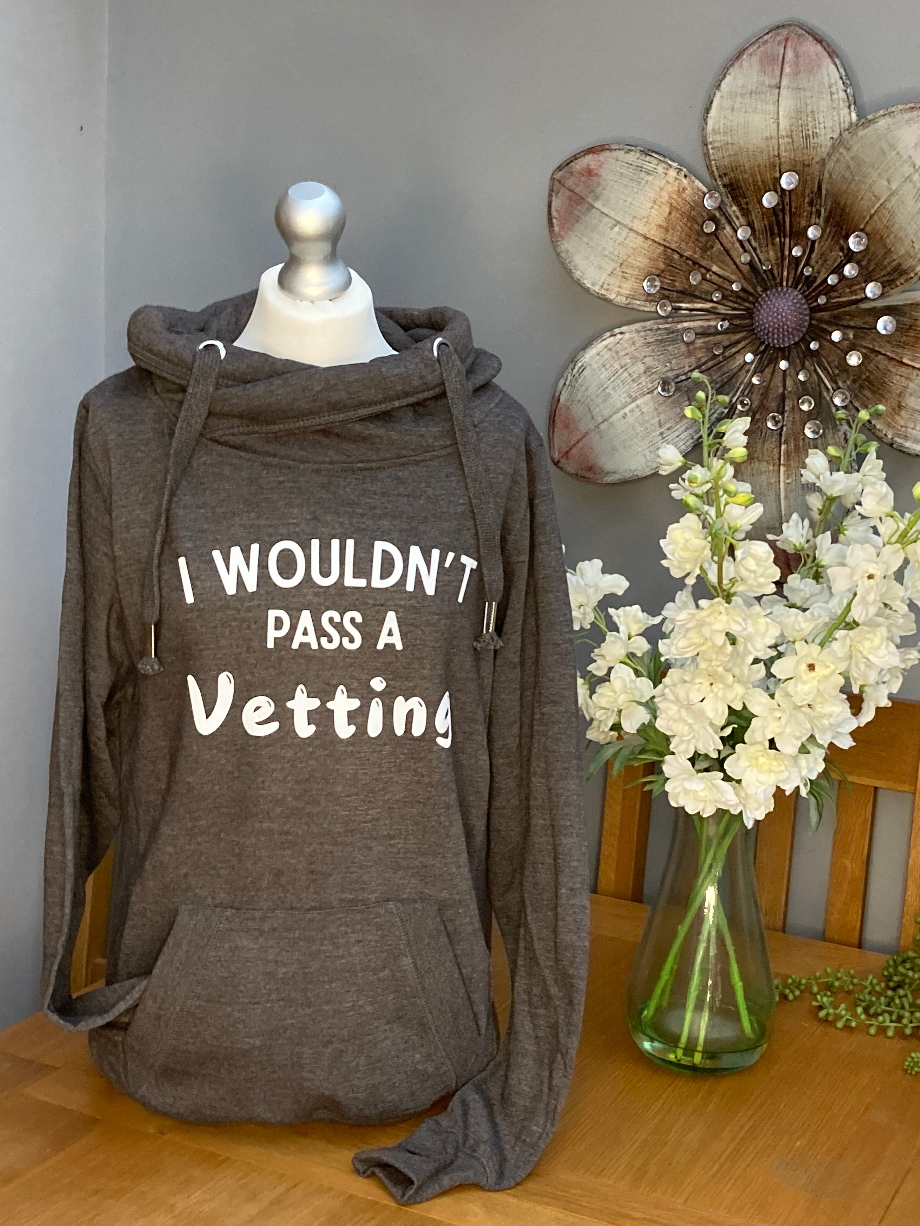 A grey cross neck hood with hood and front pocket and slogan printed on the front saying I wouldn't pass a vetting 