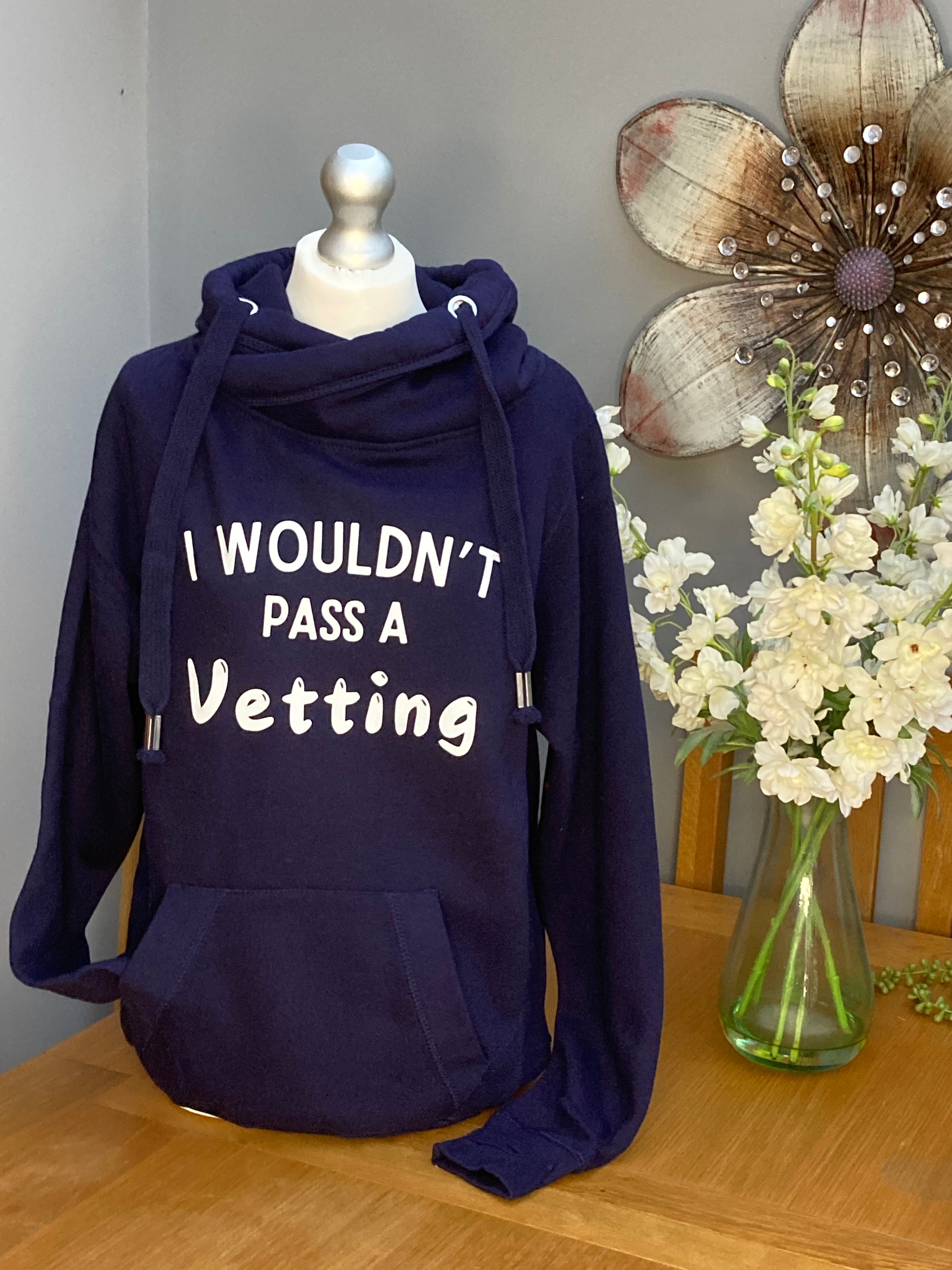A navy blue cross neck hood with hood and front pocket and slogan printed on the front saying I wouldn't pass a vetting 